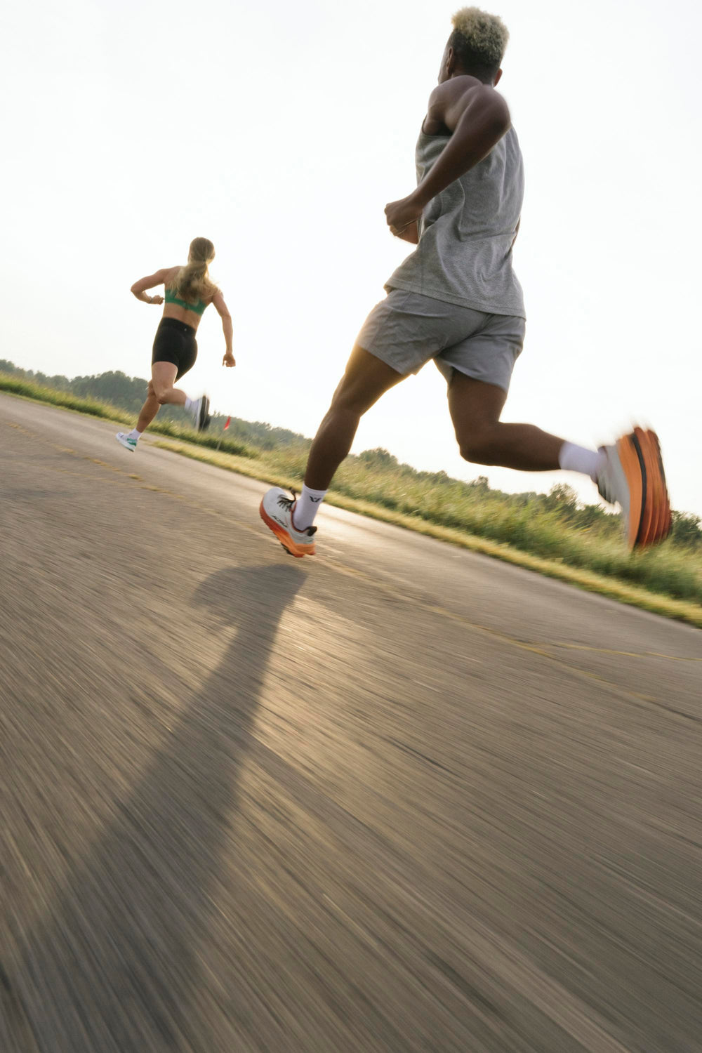 Two runners sprinting on a road during daylight.
