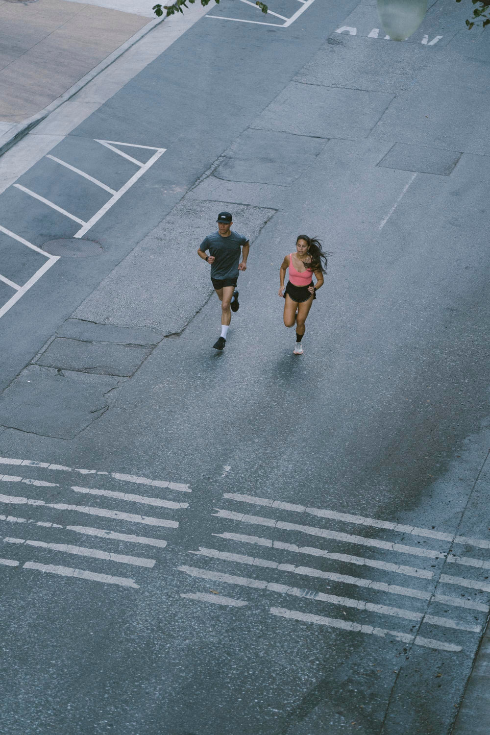 Two runners jogging on a city street, one male and one female.