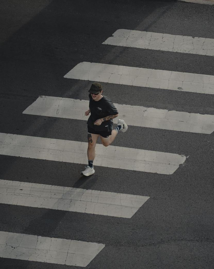 Runner crossing a city street in black Maxus Mid-Crew socks