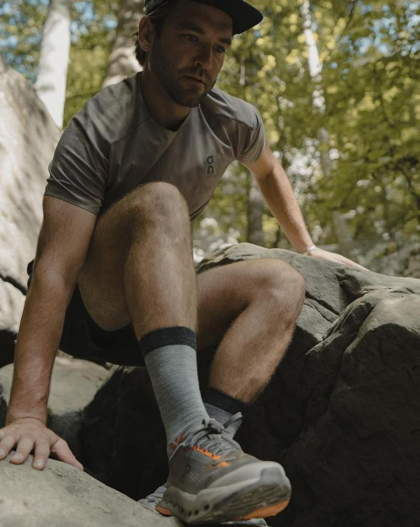 Hiker seated on rocks wearing gray Pursuit Crew socks