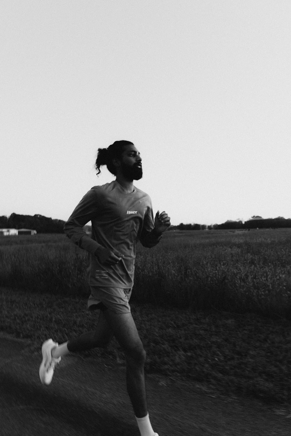 A person running in a field during sunset, wearing athletic gear.