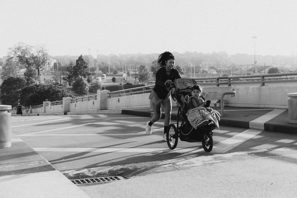 A woman running with a child in a stroller on a path.