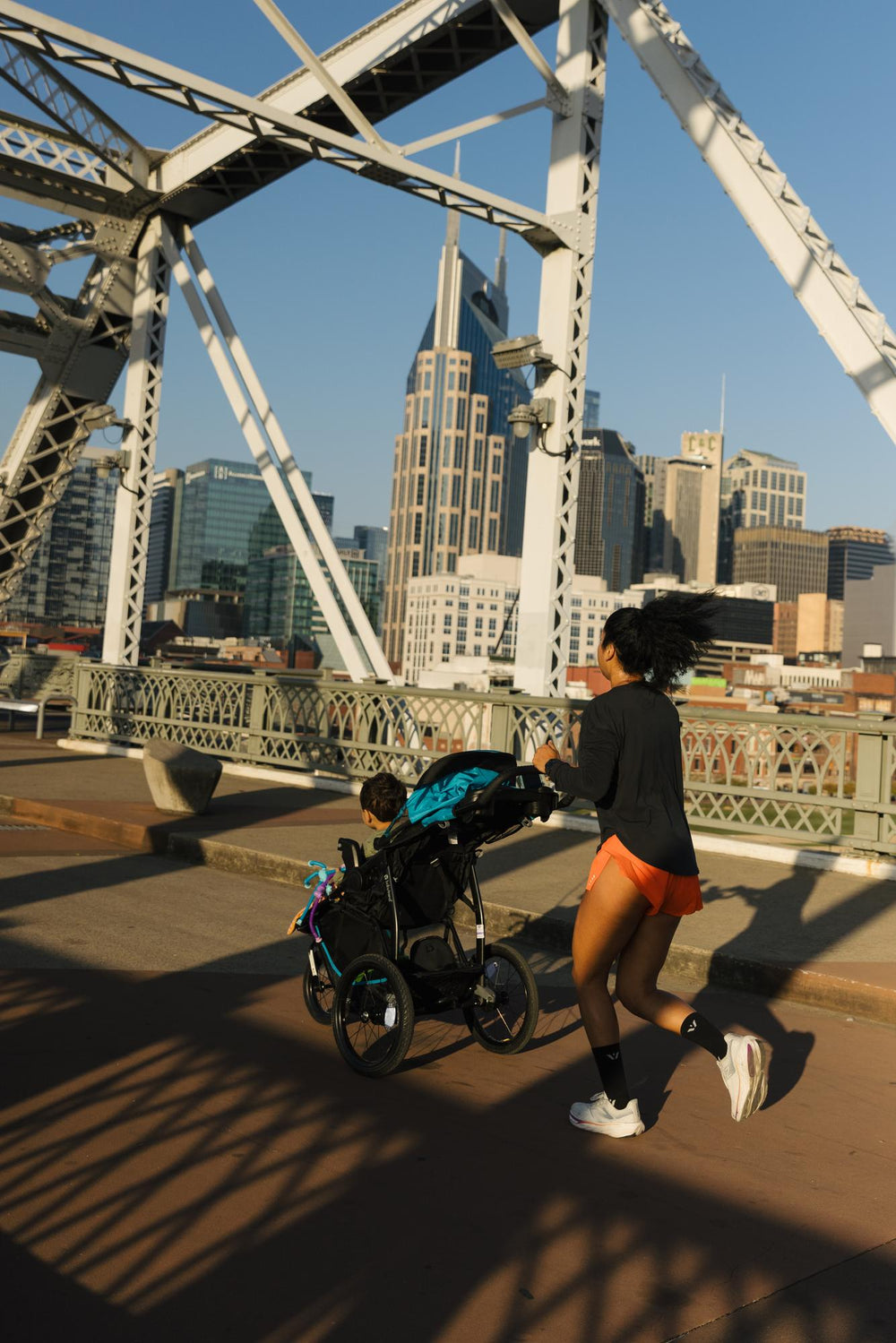 A person jogging with a stroller on a city bridge.
