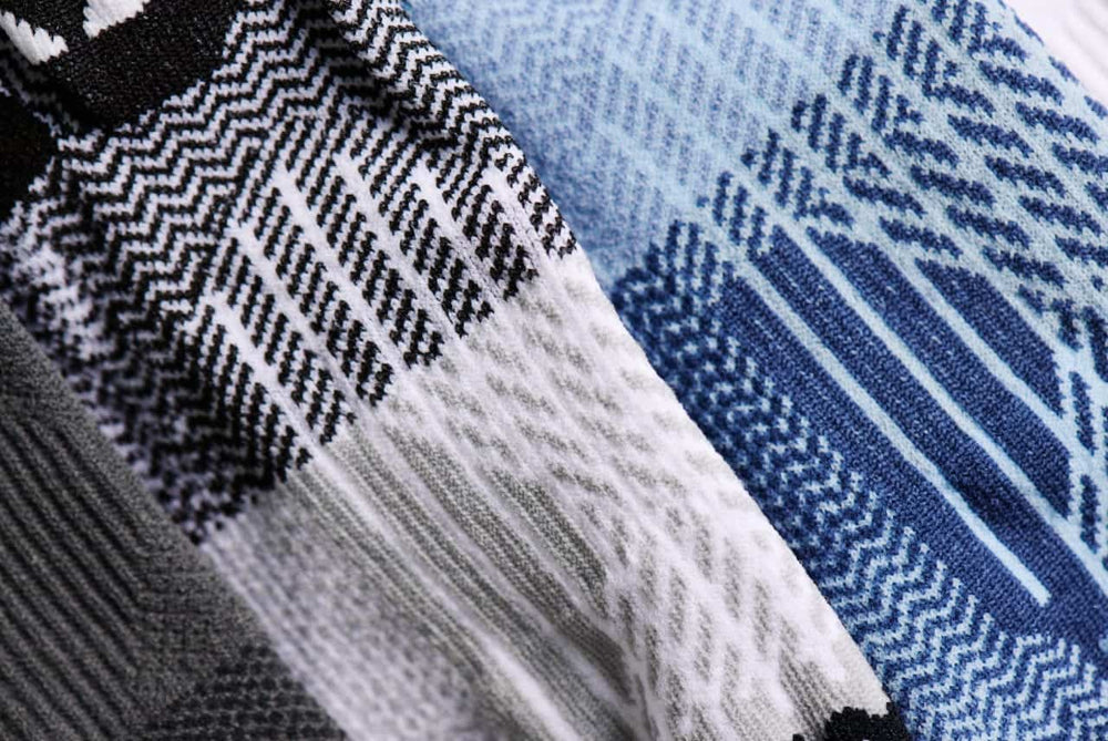 Close-up of performance socks showing knitted texture and patterned color blocks in blue, gray, black, and white