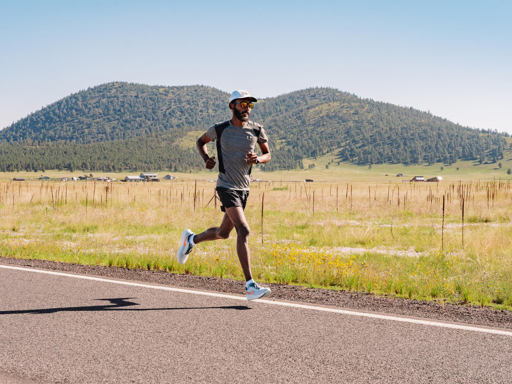 Runner wearing Maxus socks on a paved road near the mountains