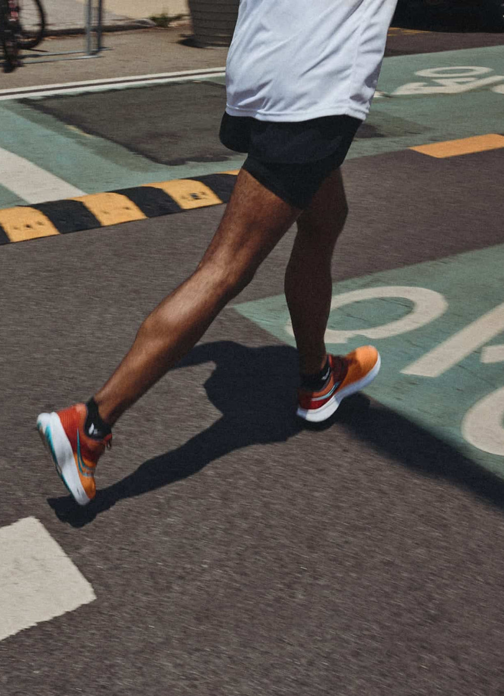 A person running on a street, showcasing athletic shoes.