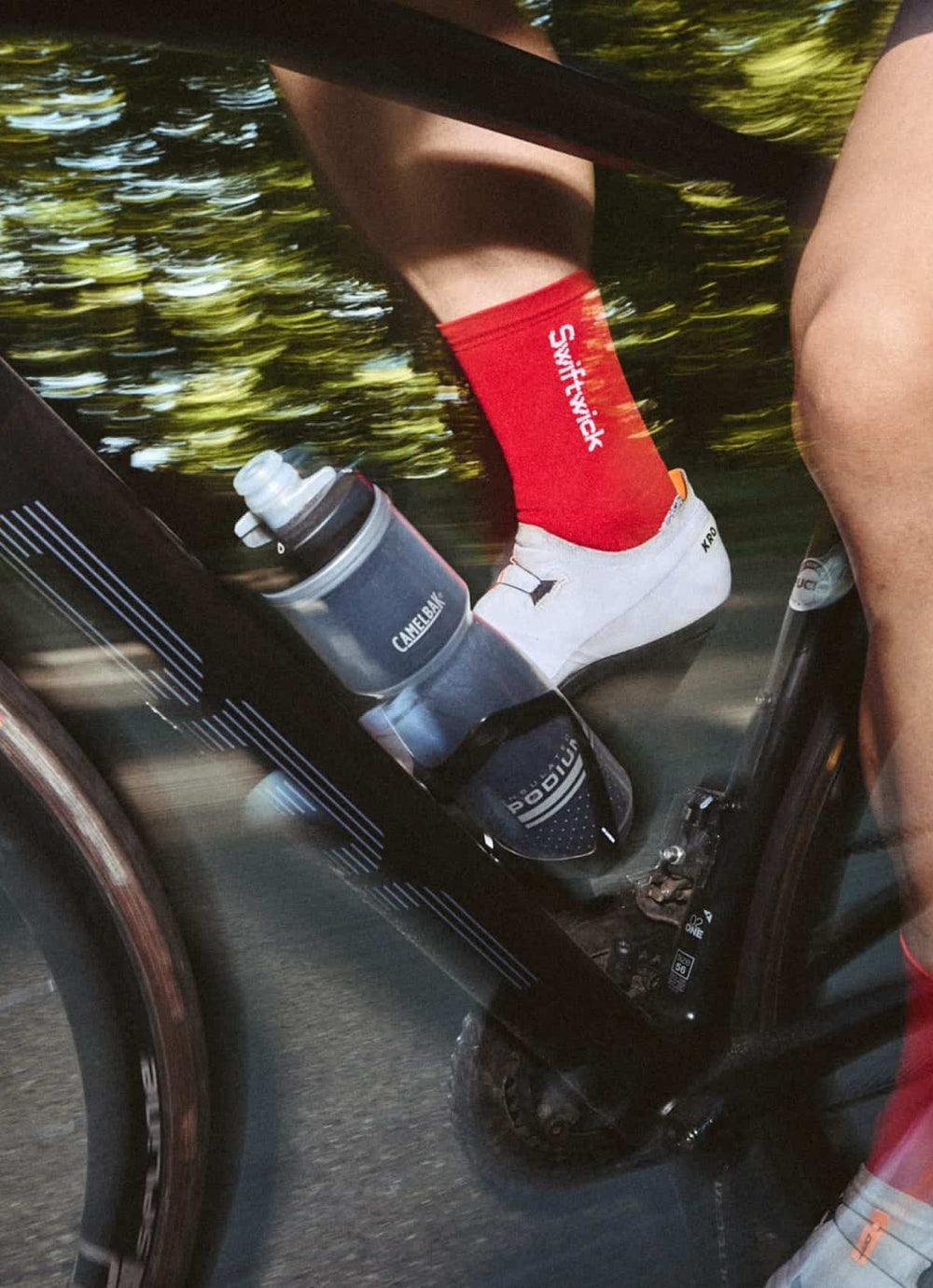 A cyclist's foot in a red sock on a bike with a water bottle.