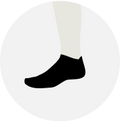 Foot wearing a no show black sock on a light background