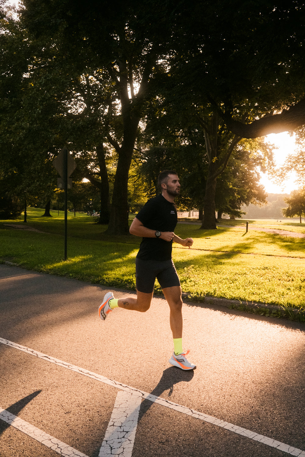 A man jogging on a path in a park during sunset.