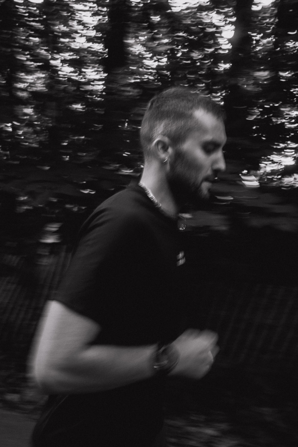 Man running along a tree-lined path, black-and-white photo with motion blur conveying speed and focus