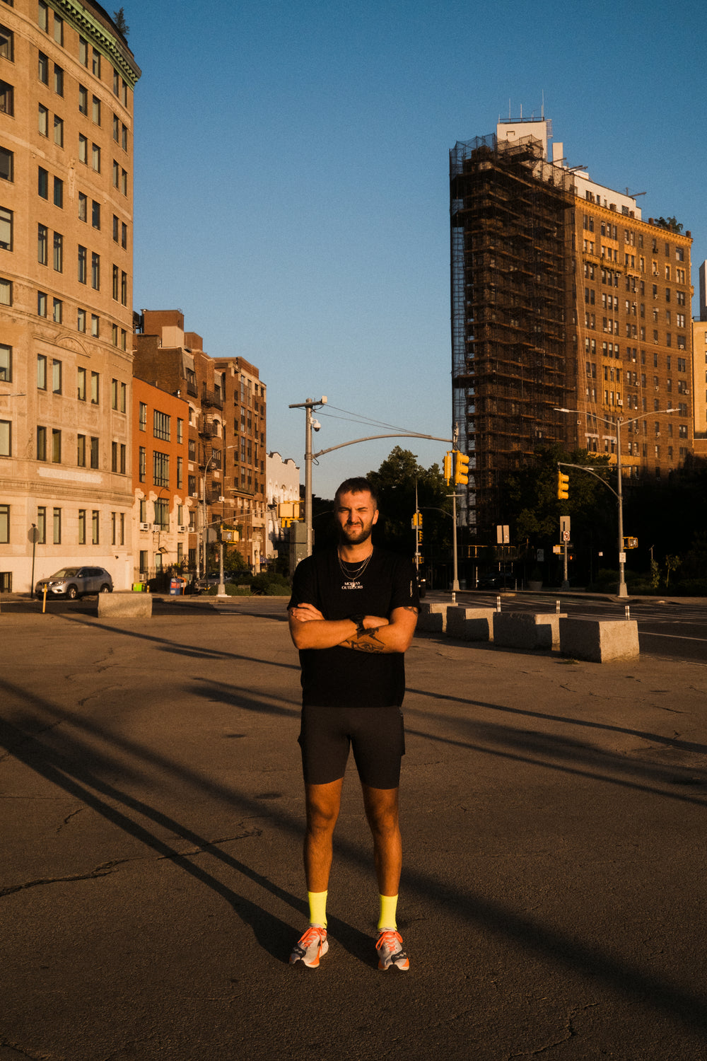 A man standing on a street with buildings in the background during sunset.