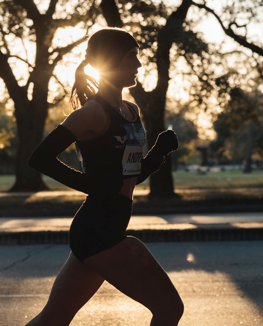 Silhouette of a runner in motion during sunset, wearing athletic gear.